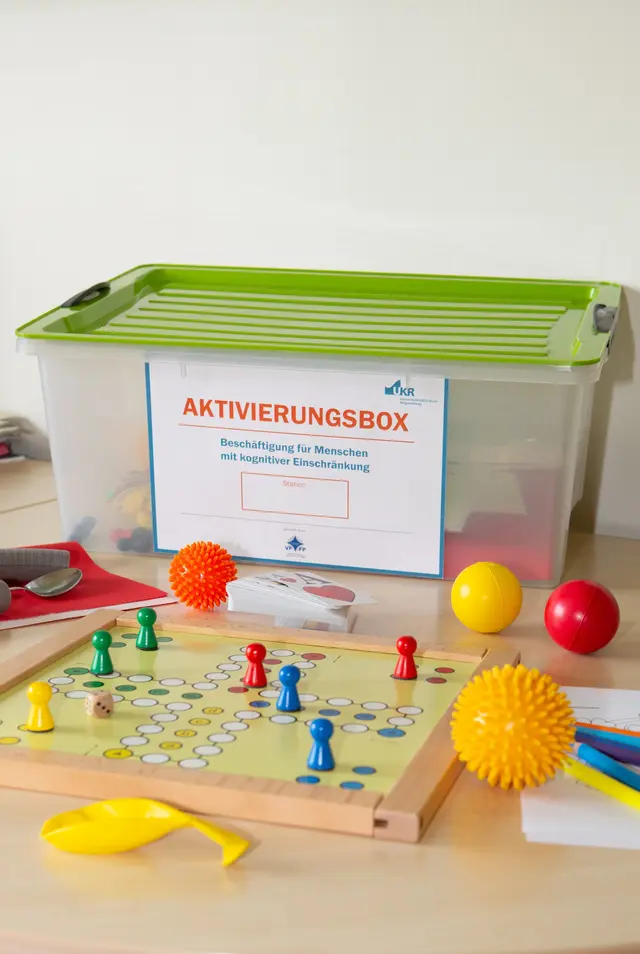 Die Aktivierungsboxen der Stationen enthalten verschiedene Materialien zur kognitiven Anregung und Orientierungsförderung wie beispielsweise Spiele, Bälle oder farbige Tischsets, ©UKR/M.Meyer